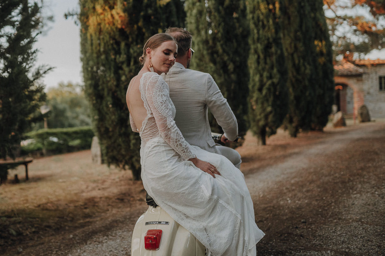 couple riding on vespa in italy at tuscany wedding venue