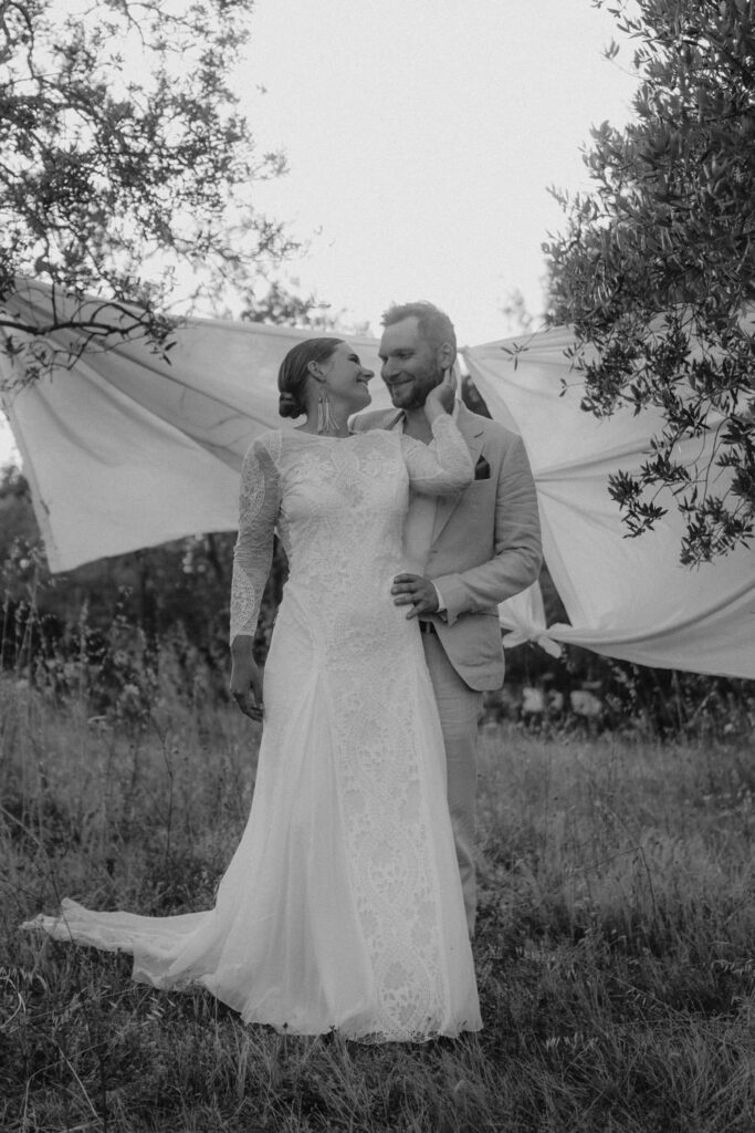 couple standing in front of white backdrop in tuscan field during couple wedding shoot.