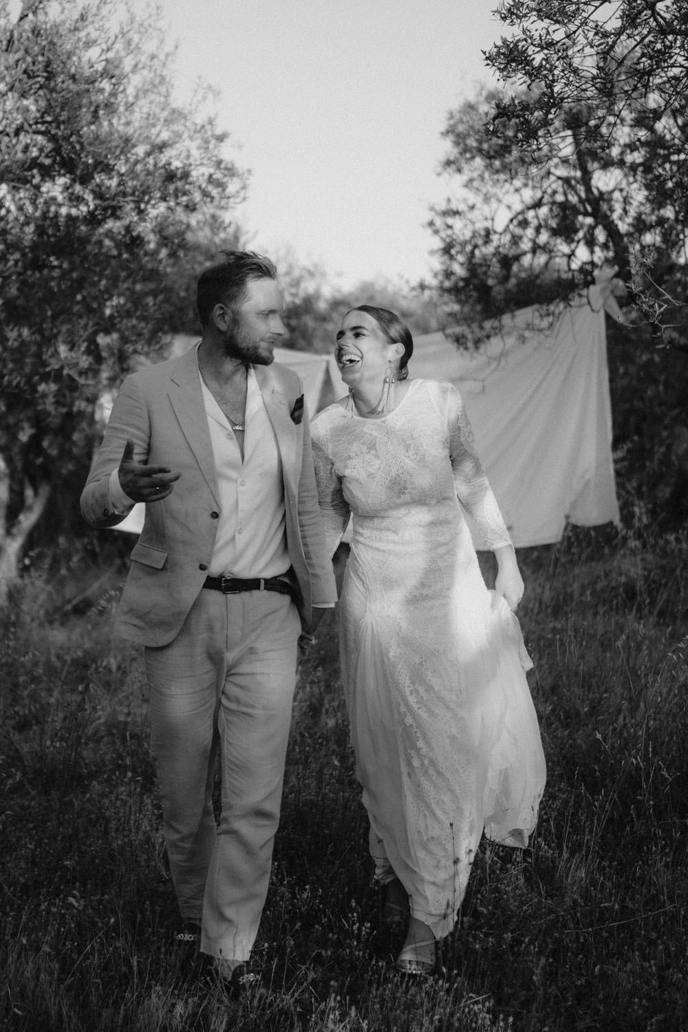 Joyful bride and groom walking through a Tuscan olive grove